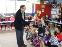 Rob Tate presents a gift to students at Whataroa School