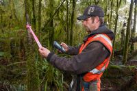 Contractor using a personal digital assistant while undertaking ground control of possums. – TBfree New Zealand